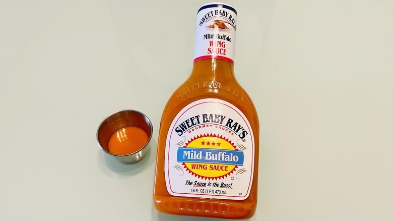Bottle of Sweet Baby Ray's Mild Buffalo Wing Sauce with ramekin on side