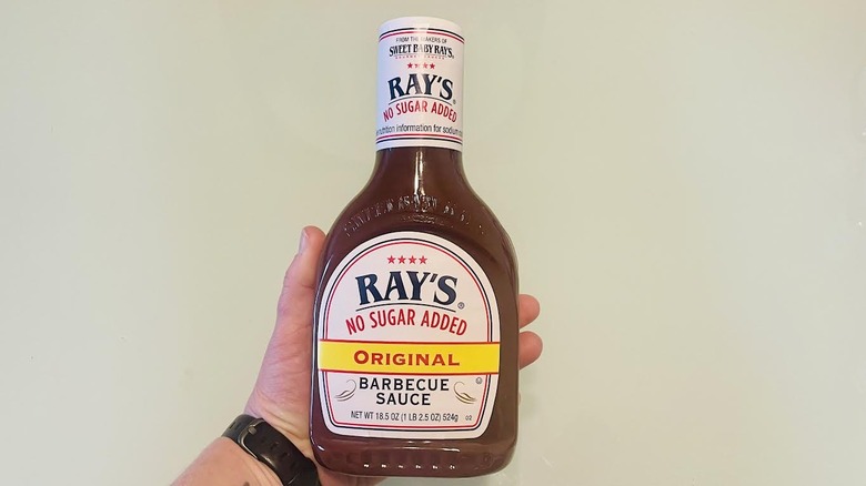 Hand holding bottle of Sweet Baby Ray's No Sugar Added Original Barbecue Sauce