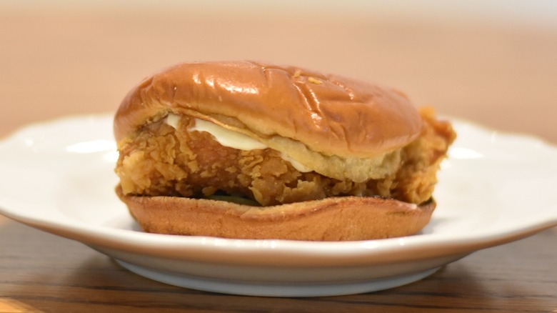 A Popeyes chicken sandwich with mayo on a white plate