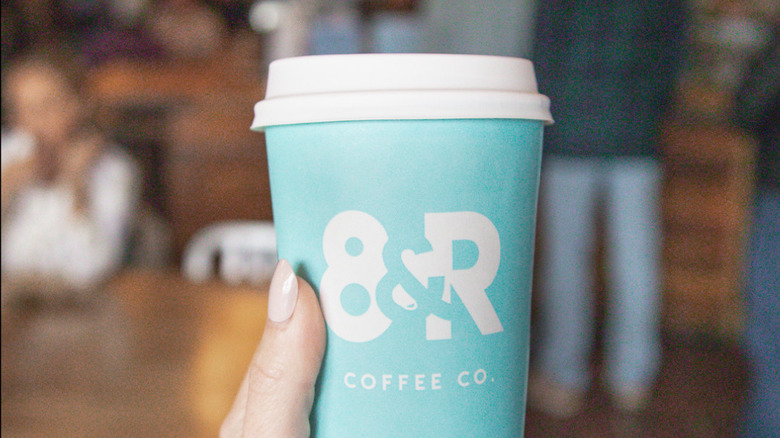 A female customer holding her 8th & Roast beverage