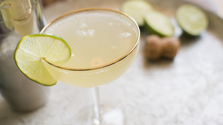 A daiquiri with a lime in a coupe glass on a table