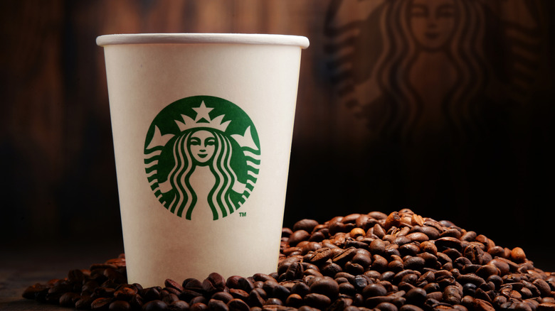 A plain starbucks cup atop beans