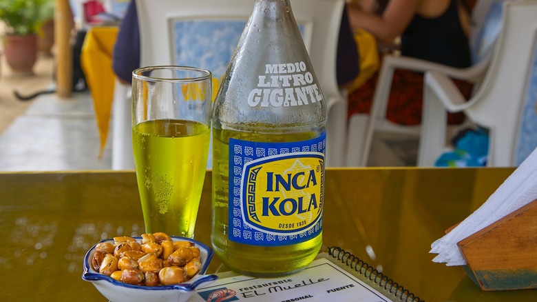 Glass of Inca Kola with large Inca Kola bottle in restaurant