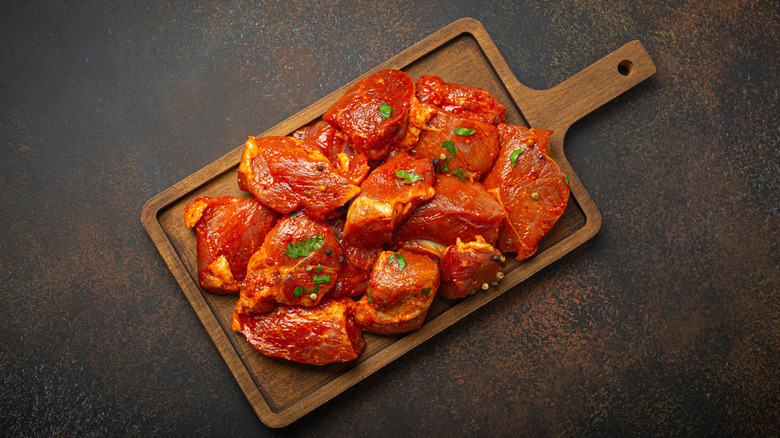chunks of marinated pork on a wooden board