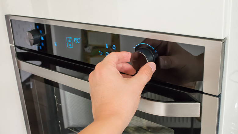 Person adjusting a dial on the oven