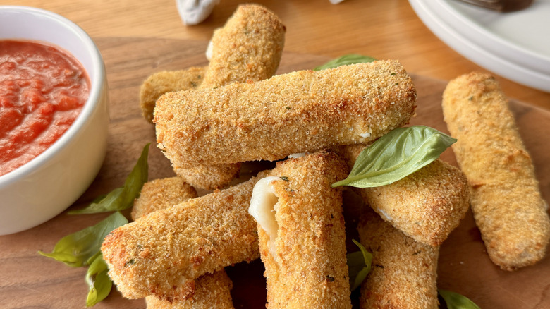 mozzarella sticks next to a bowl of tomato sauce