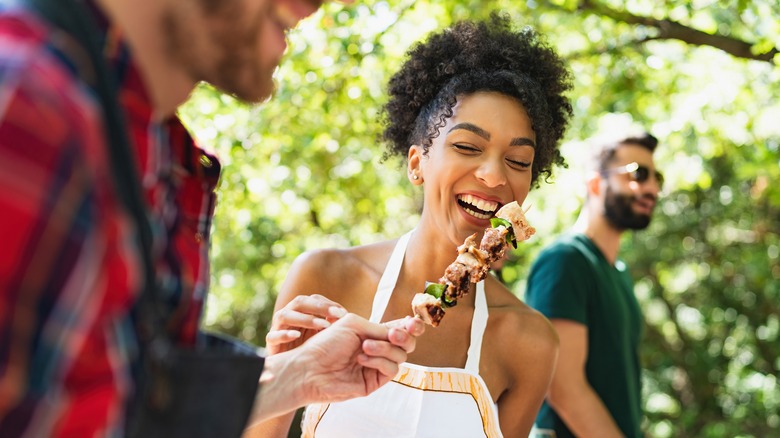 woman tasting meat skewer