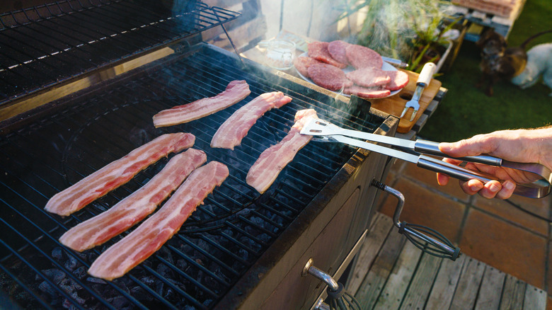 Horizontal close-up view of man cooking meat at spanish barbecue party with friends at summer