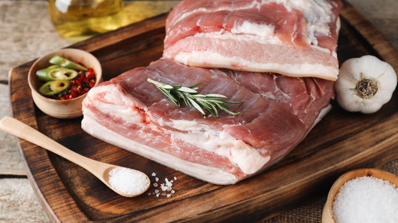 bacon and additives like rosemary, salt, chile, and garlic on a board