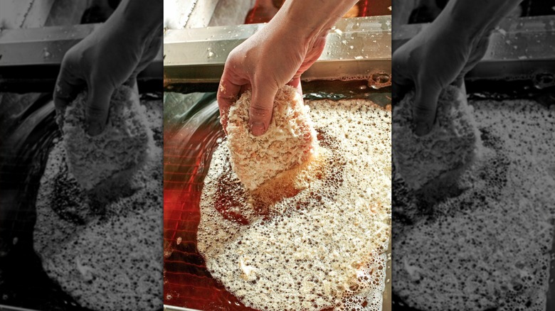 Person breading a pork chop for frying
