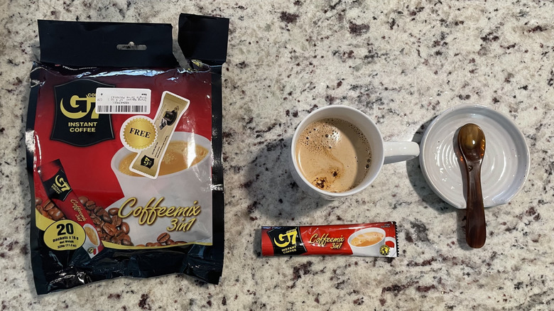 Trung Nguyen coffee packaging is next to a cup of coffee and a spoon on a saucer.