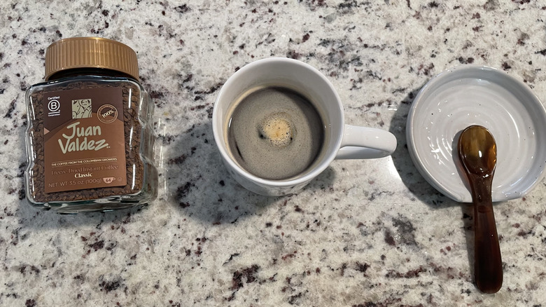 Juan Valdez Coffee packaging is next to a cup of coffee and a spoon on a saucer.