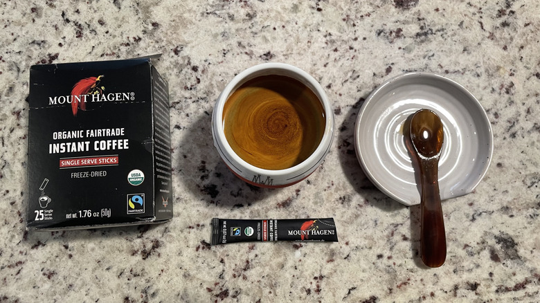 Mount Hagen coffee packaging is next to a cup of coffee and a spoon on a saucer.