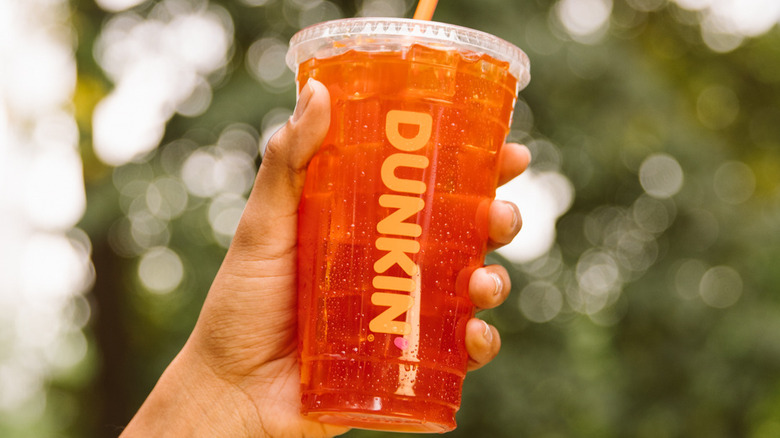 A person holding Blood Orange Refresher with a background of trees