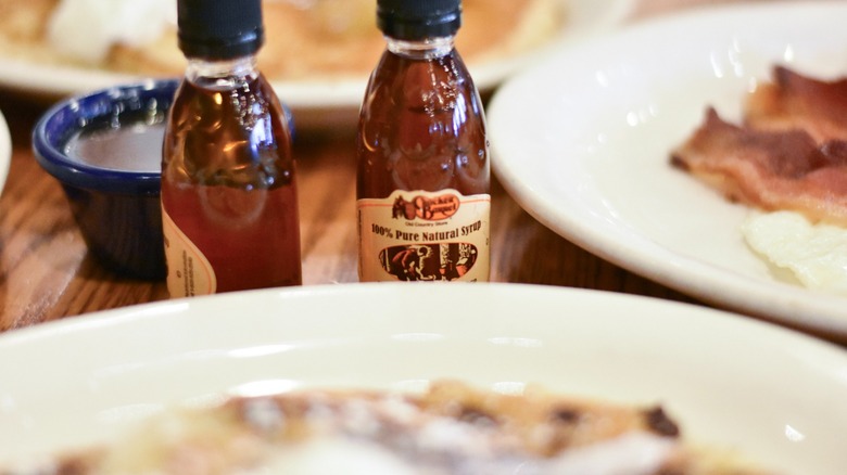 Cracker Barrel syrup next to a white plate with blueberry pancakes