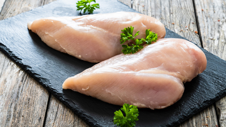 Raw chicken breasts on cutting board