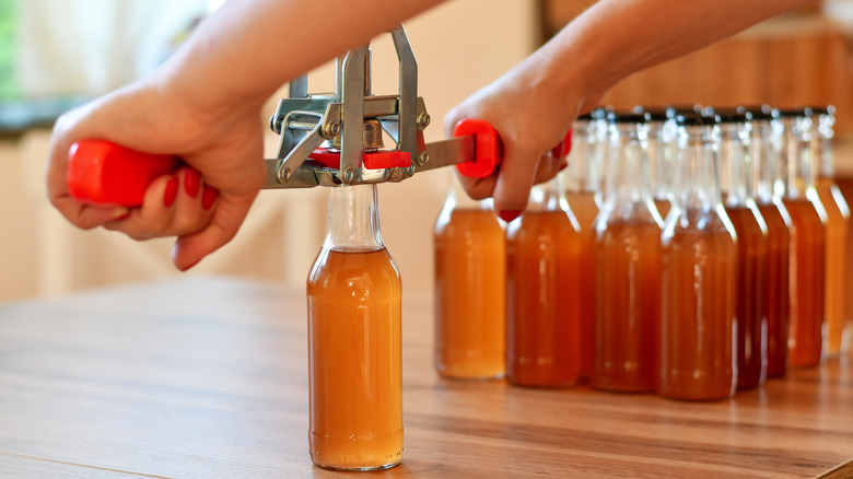 Man using hand capper for bottling beer