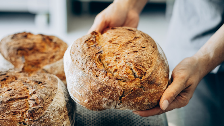 A baker holding a freshly baked loaf of bread