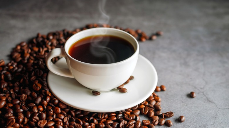 coffee in white mug on white saucer with coffee beans