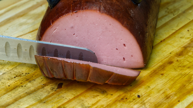 Whole smoked bologna being sliced