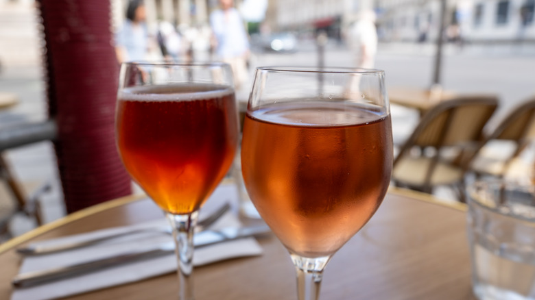 Two Kir Royales in closeup with a restaurant patio in the background.