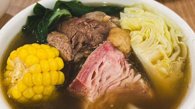 Close up bowl of bulalo with corn cob and cabbage