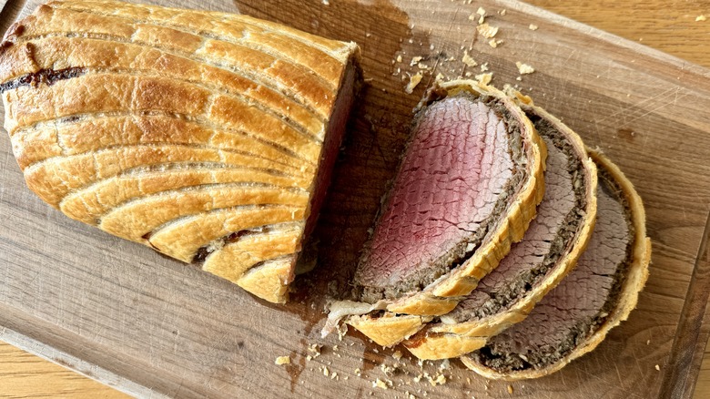 sliced beef wellington on wooden board