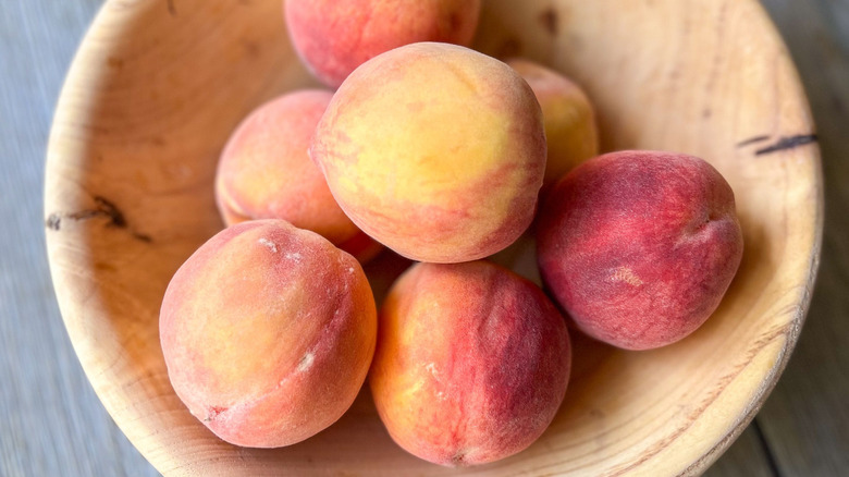 Fresh peaches in wooden bowl