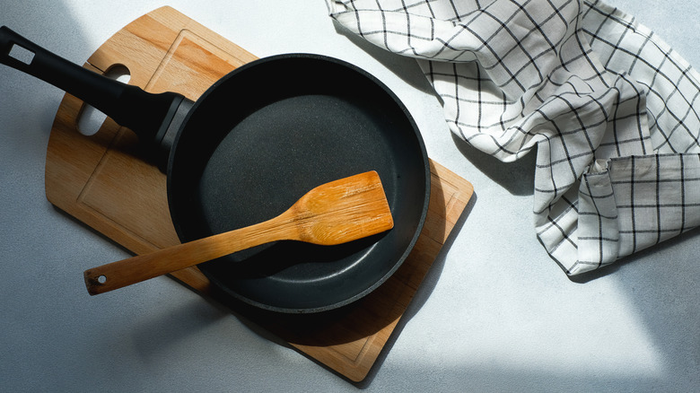 Cast iron skillet with a wooden spatula resting on a cutting board