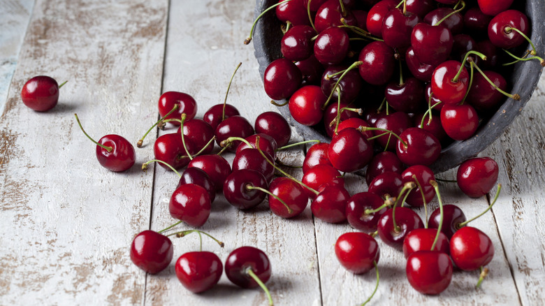 Bowl of cherries spilling on wooden table