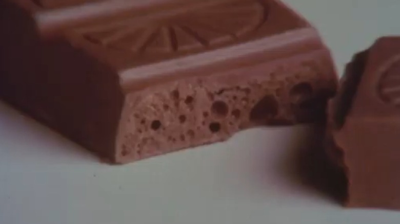 Image from Choco'Lite commercial showing candy bar cut in half with an orange-segment pattern on top of one piece of chocolate and a honeycomb-like center