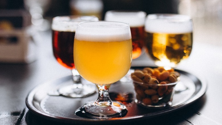 Several different types of beer on a serving tray with nuts