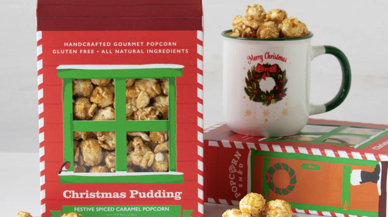 A box of Christmas pudding popcorn next to a mug with more popcorn in it