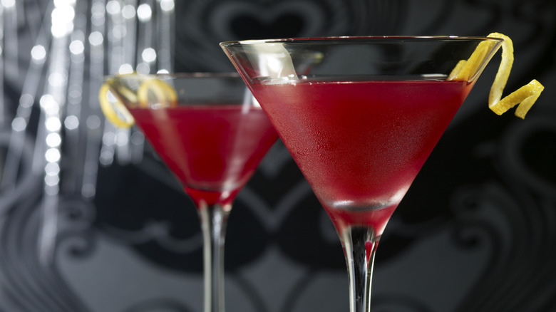 Pink cocktail in a martini glass garnished with a lemon twist