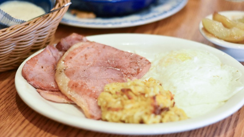 Eggs with ham, hashbrowns, fried apples, and a basket of biscuits and gravy