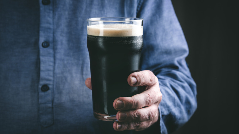 Person holding glass of dark beer