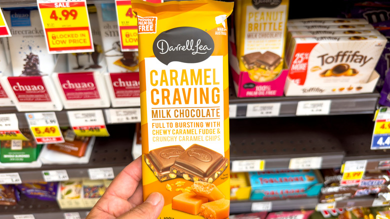 A person holding a Darrell Lea Caramel Craving chocolate bar at a store