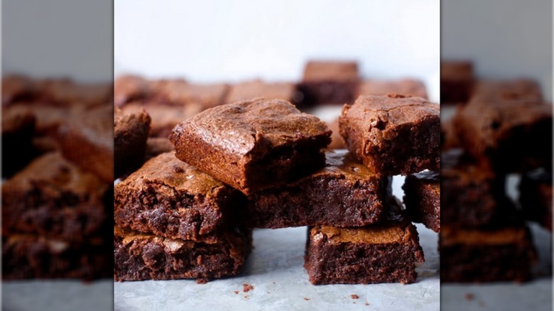A pile of chocolate brownies on a sheet of white baking parchment