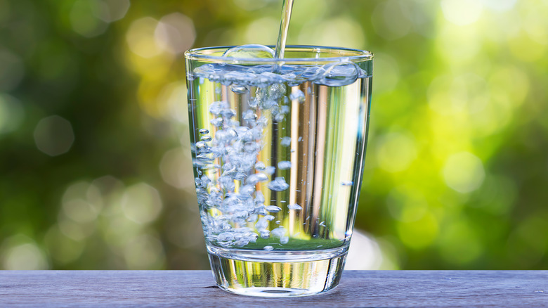 A glass being filled to the top with clear water
