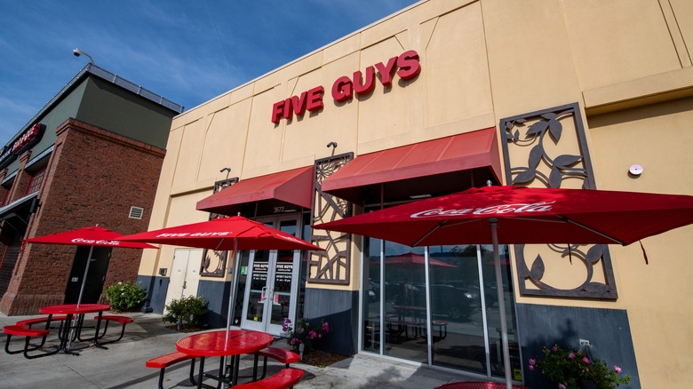 The exterior of a Five Guys with outside seating