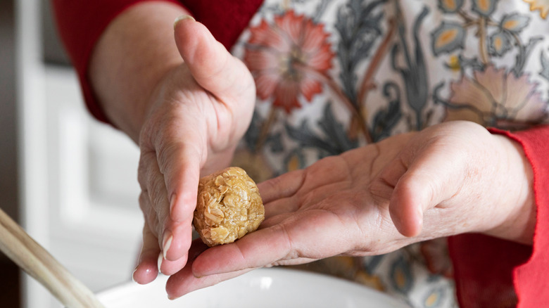 Hands rolling oatmeal cookie dough