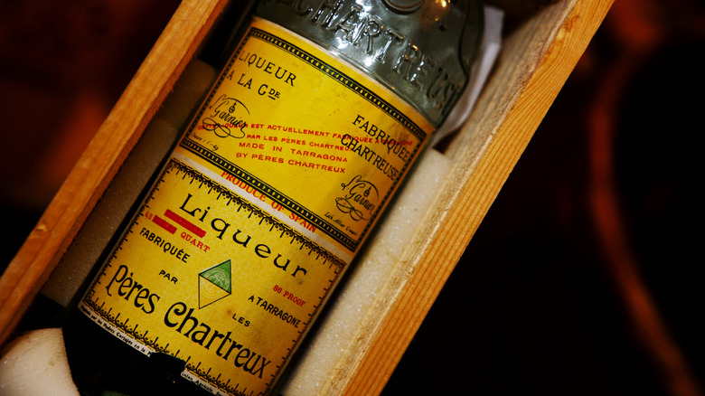Bottle of Chartreuse liqueur in old bottle and wood case
