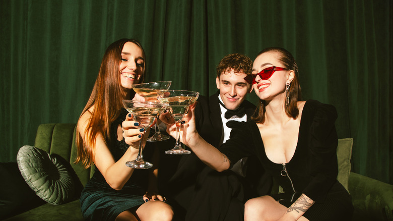 Three people cheers with martinis