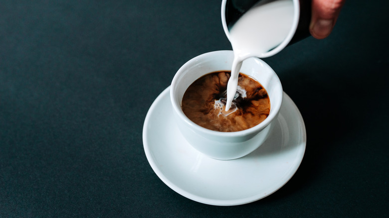 Cream pouring into a cup of coffee