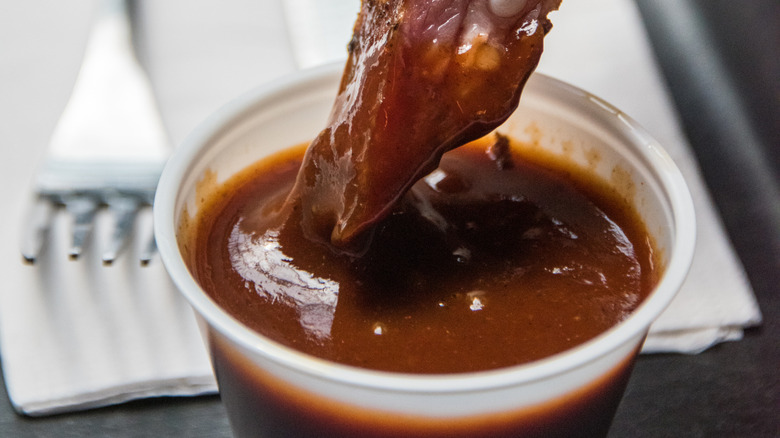 meat being dipped into barbecue sauce