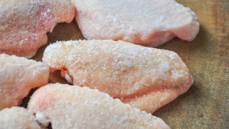 Frozen raw chicken wings on the cutting board.