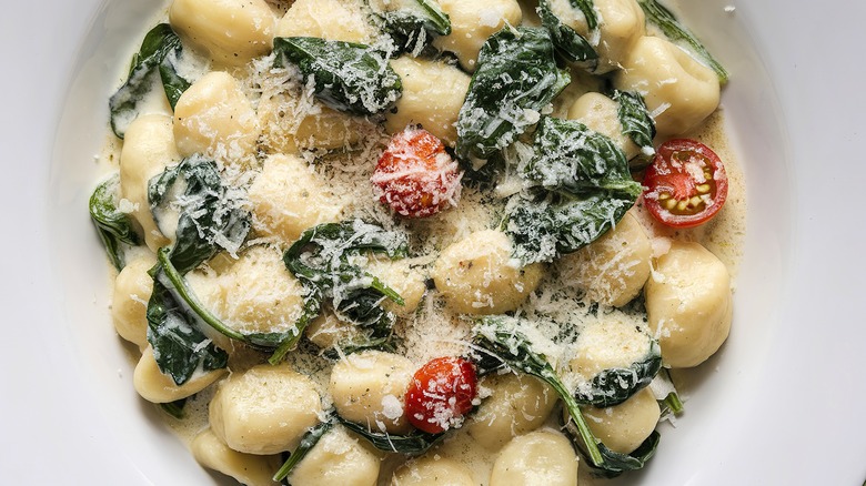 Overhead shot of gnocchi with spinach and tomatoes