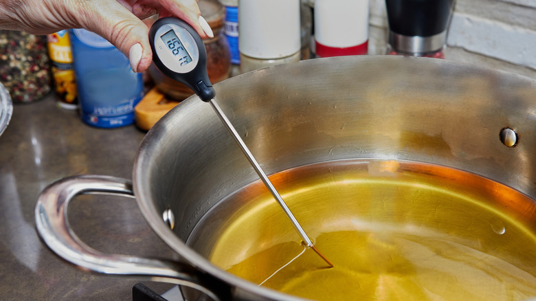 Person taking temperature of cooking oil