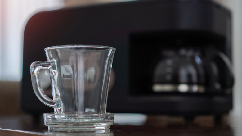 Coffee cup with drip coffee machine in the background