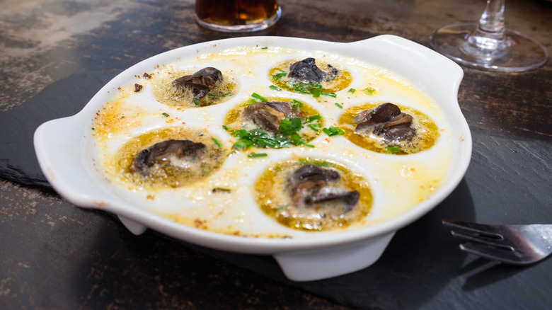 Escargot in hot, herb butter in a specialty escargot dish without the shells.
